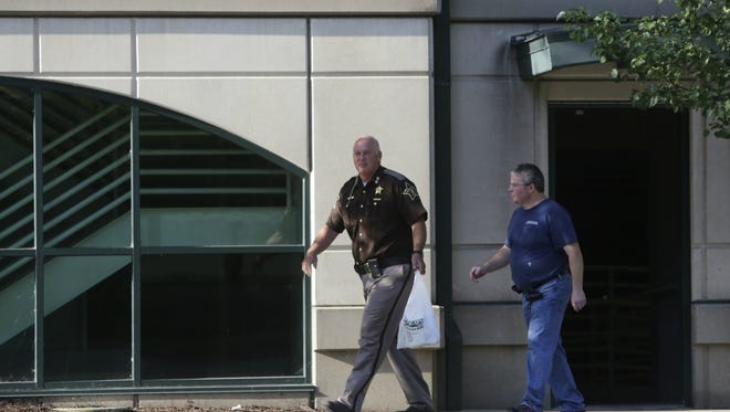 Tippecanoe County Sheriff Barry Richard and a maintenance worker exit the parking garage at Columbia and Second streets Monday, July 27, with a pressure cooker full of pork, which prompted a suspicious package report that briefly closed the garage.