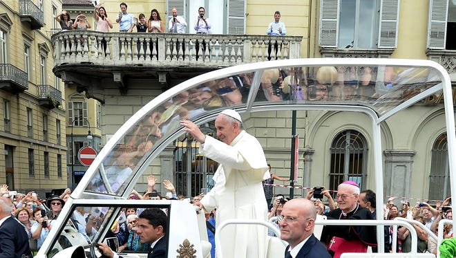 Pope Francis waves to the faithful Monday, June 22, 2015, on his way to Turin's airport to return to the Vatican. Francis earlier entered the Waldensian temple of Turin on the second day of his visit to the land of his ancestors, becoming the first pope to visit a Waldensian evangelical church, whose members were persecuted by the Catholic Church during the Middle Ages.