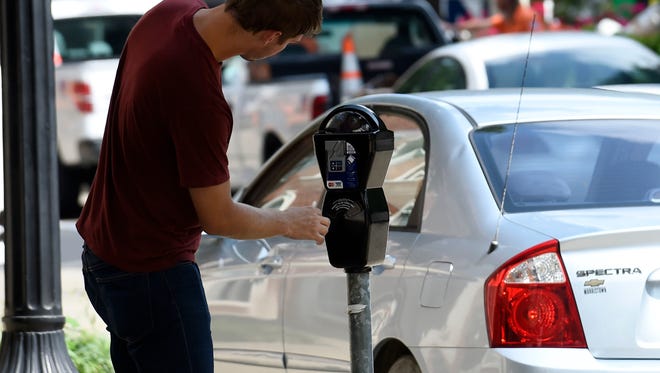 Nick Martin reads instructions on a new parking meter on Market Street. As city officials continue to make the push for quicker turnover in short-term parking spaces, sensors in about 1,000 new parking meters installed in August in downtown and Fort Sanders are being activated this month.