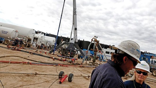 Travis Allen, left, Basin Well Logging & Perforating supervisor, and Susan Alvillar, WPX community affairs representative, discuss operations at a WPX Energy fracking site at Turtle Mountain in Lybrook in 2015.