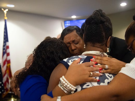 Karen Crosby, center, embraces four other black women