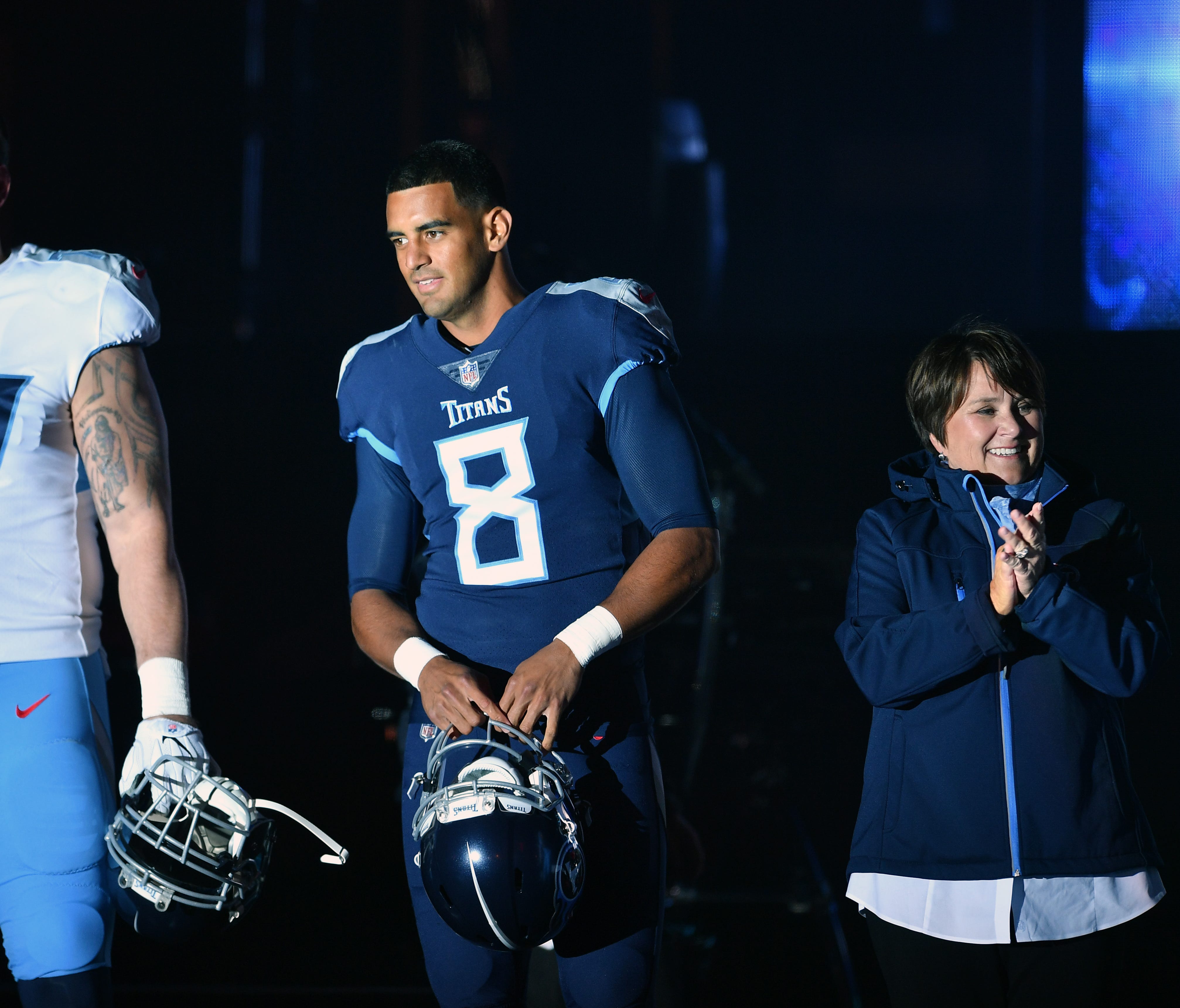 Tennessee Titans offensive tackle Taylor Lewan (77) and Tennessee Titans quarterback Marcus Mariota (8) show off new their uniforms with Titans owner Amy Adams Strunk by their side during a block party downtown Nashville on Wednesday, April 4, 2018.