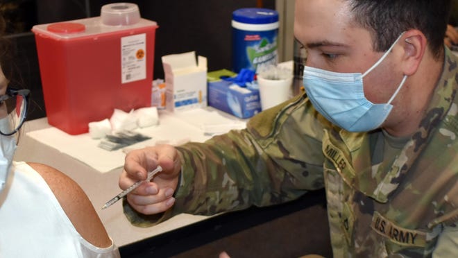 An Army National Guard medic administers a second dose of the Pfizer vaccine Thursday in Coldwater.