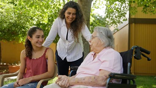 In this photo taken Monday, July 6, 2015, Kamila Al-Najjar, center, visits with her mother, Joan Groen, right, at her assisted living facility as her daughter, Inanna Al-Najjar, 14, left, looks on in Santa Rosa, Calif.  Caught between kids and aging parents, a new poll shows the sandwich generation worries more than most Americans their age about how they'll afford their own care as they grow older.  (AP Photo/Eric Risberg)