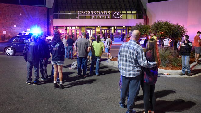 People stand near the entrance on the north side of Crossroads Center between Macy's and Target Saturday night as officials investigate a reported multiple stabbing incident. 