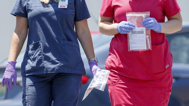 Nurse Melissa Bailey, left, and medical assistant Heather Andrews carry collected samples at DeKalb Regional Medical Center's drive thru COVID-19 testing site on Thursday, July 16, 2020 in Fort Payne, Ala.