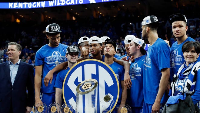 Kentucky head coach John Calipari, left, and his players accept their trophies after beating Tennessee in an NCAA college basketball championship game at the Southeastern Conference tournament Sunday, March 11, 2018, in St. Louis. Kentucky won 77-72. (AP Photo/Jeff Roberson)