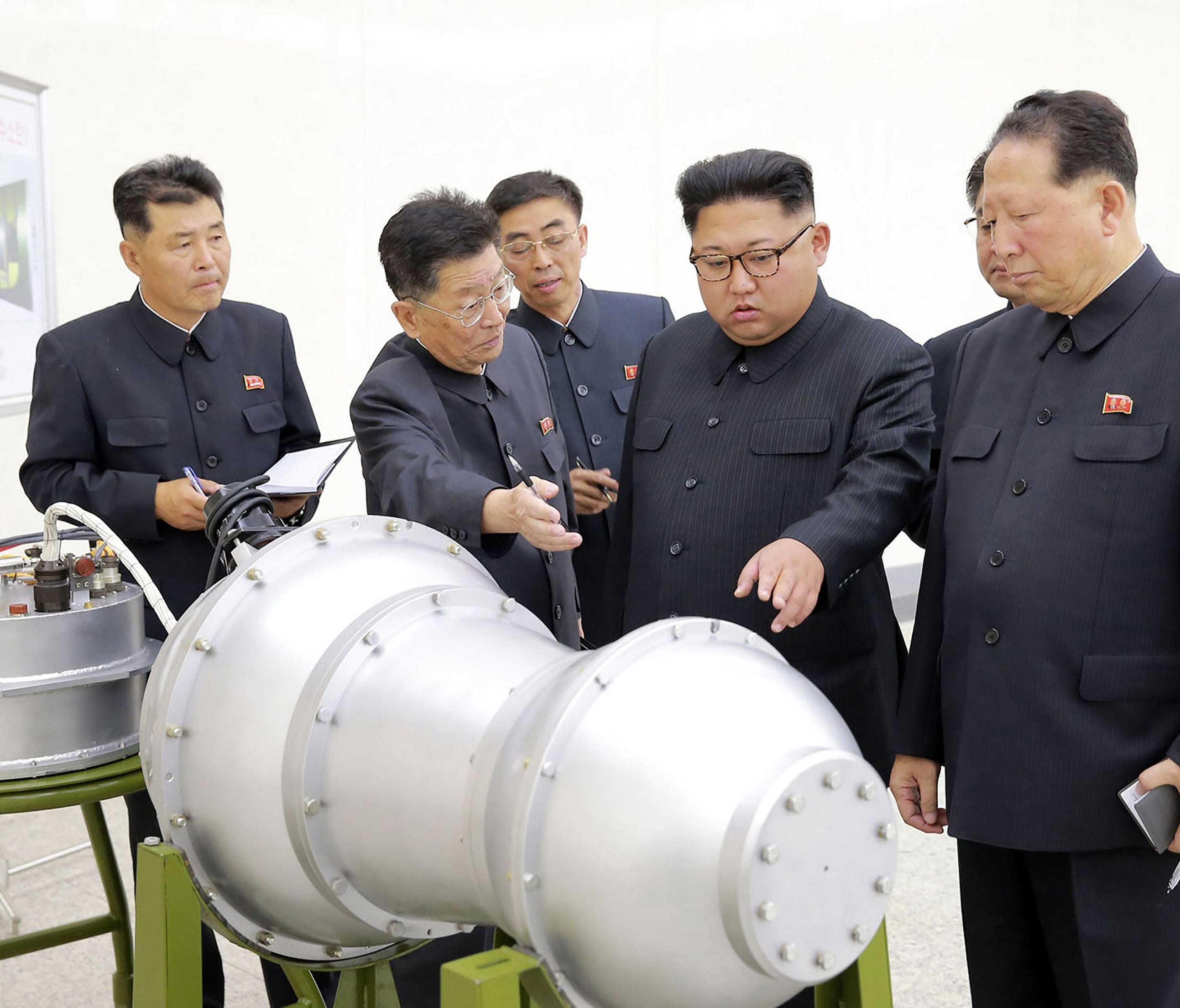 This undated picture released by North Korea's official Korean Central News Agency (KCNA) shows North Korean leader Kim Jong-Un (C) looking at a metal casing with two bulges at an undisclosed location.