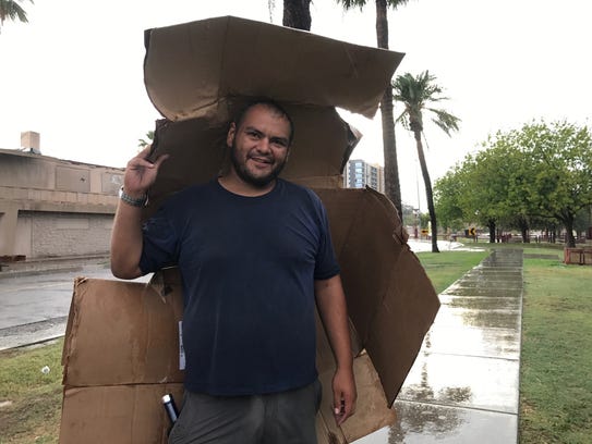 Adolph Gutierrez, 32, tries to stay dry during a monsoon