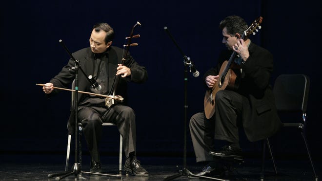 Dr. Ming Wang, president of the Tennessee Chinese Chamber of Commerce, plays a Chinese erhu violin beside classical guitarist Carlos Enrique at a Chinese New Year celebration.