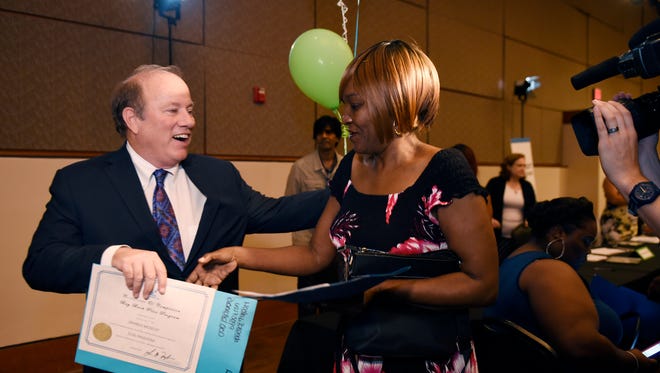 Mayor Mike Duggan,(l), gives Zranda Mosley, 59, of Detroit her deed for her home during the program.