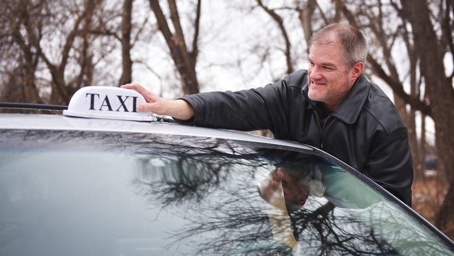 Former cab driver for 1st American Cab Company Todd Ellingson puts his old taxi light on his retired cab Friday, Feb. 2, outside of his home in Sioux Falls. Ellingson has already folded 1st American Cab in favor of a new business pursuit.
