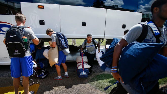 Members of the University of Memphis football team grab their gear from a charter bus after arriving on the Lambuth Campus for three days of preseason training camp.