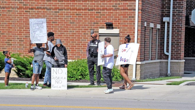 Juan McCloud, detective at the Wooster Police Department, talks with Legacy Blair, Lasheika Blair, King Blair, Kellon Wallace, Braylon Wallace and Tavieanna Blair during their protest in front of the police department on Friday.