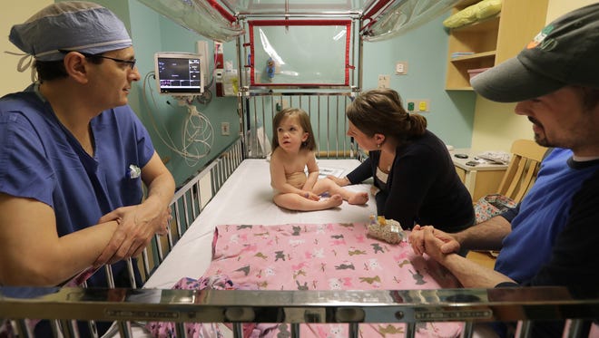 Dr. Bermans Iskandar, left, talks in May with Nina Maroszek Brennan and Ryan Brennan before performing spinal surgery on their daughter, Avi, at American Family Children's Hospital in Madison. The surgery was done to help Avi with kidney damage, bladder pressure and lower extremity contractures.