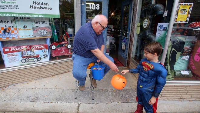 Steve Holden of Holden Hardware hands out candy to Elliott Huckaby during Halloween on the Square on Oct. 28, 2015.