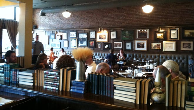 Books create a room divider between the bar and restaurant in the Tavern in Tulsa, Okla. The books are arranged in an Art Deco-style geometric pattern.