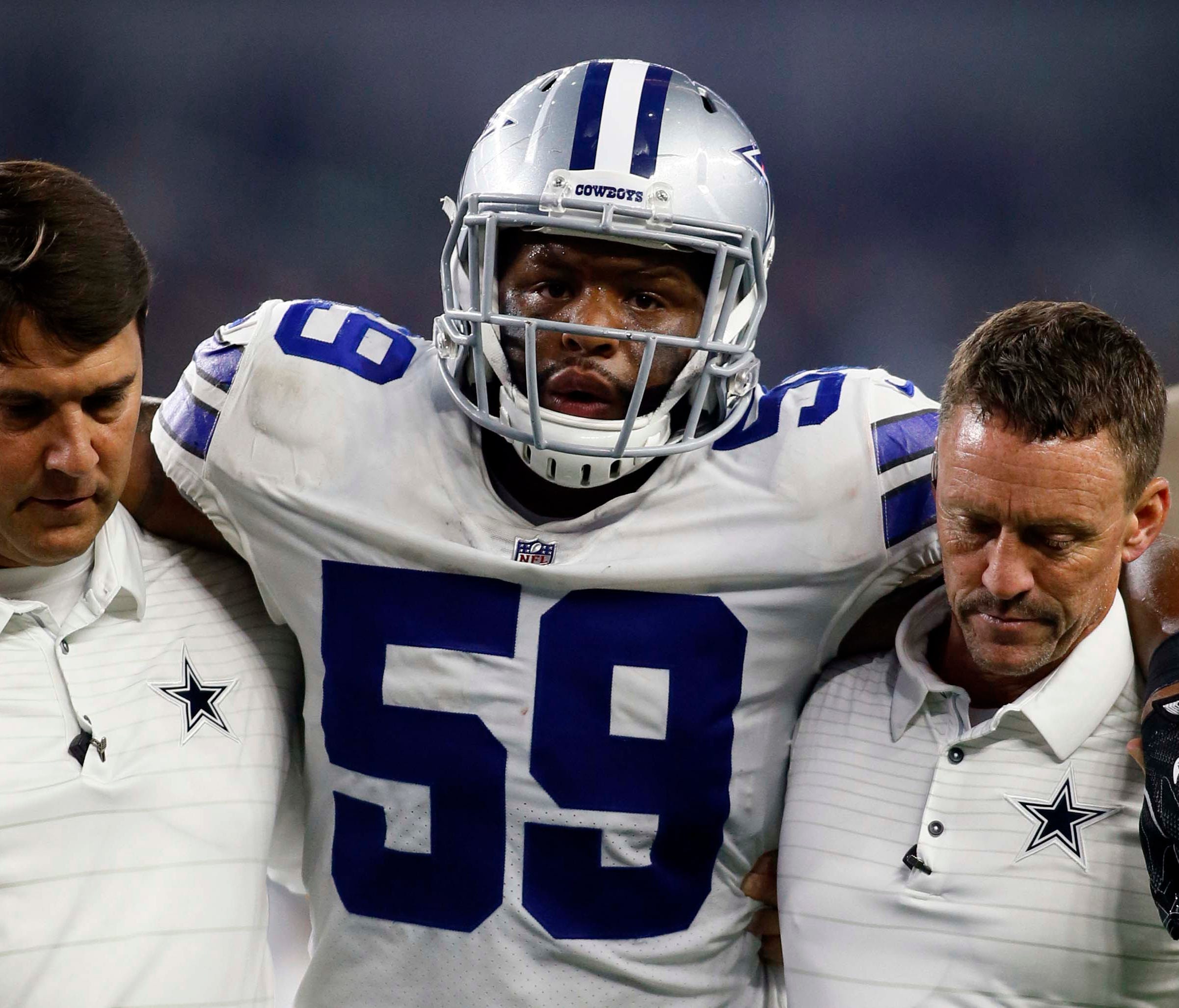 Dallas Cowboys middle linebacker Anthony Hitchens (59) is helped off the field by Dallas Cowboys trainers in the second quarter at AT&T Stadium.