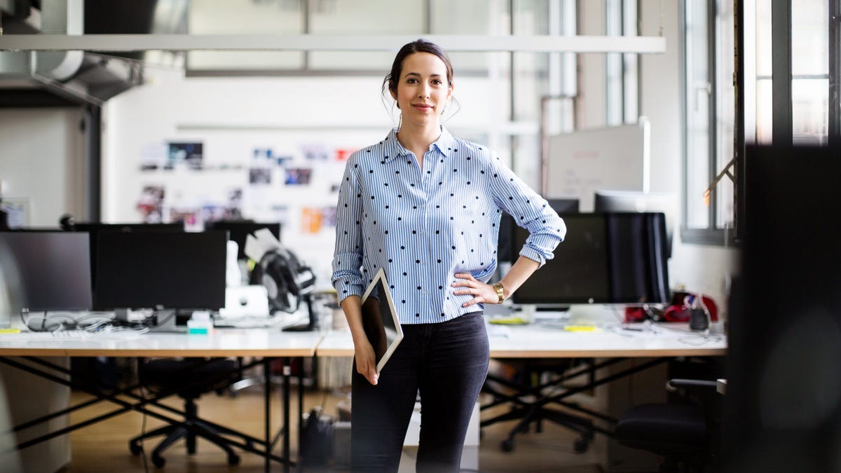 Person holding tablet standing in front of desk