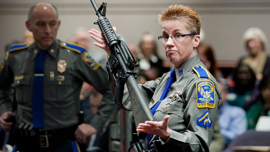 Firearms training unit Detective Barbara J. Mattson, of the Connecticut State Police, holds up a Bushmaster AR-15 rifle, the same make and model of gun used in the Sandy Hook School shooting, during a hearing of a legislative subcommittee in Hartford, Conn., Jan. 28, 2013.