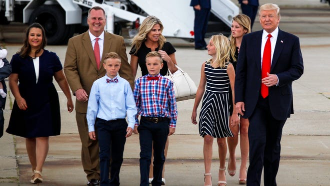 President Donald Trump walks with the Whalen family, left, of Dayton, Ohio and the Withrow family of Louisville, Ky. Wednesday, June 7, 2017 at Lunken Municipal Airport in Cincinnati, Ohio. President Trump identified the families as "victims of Obamacare."