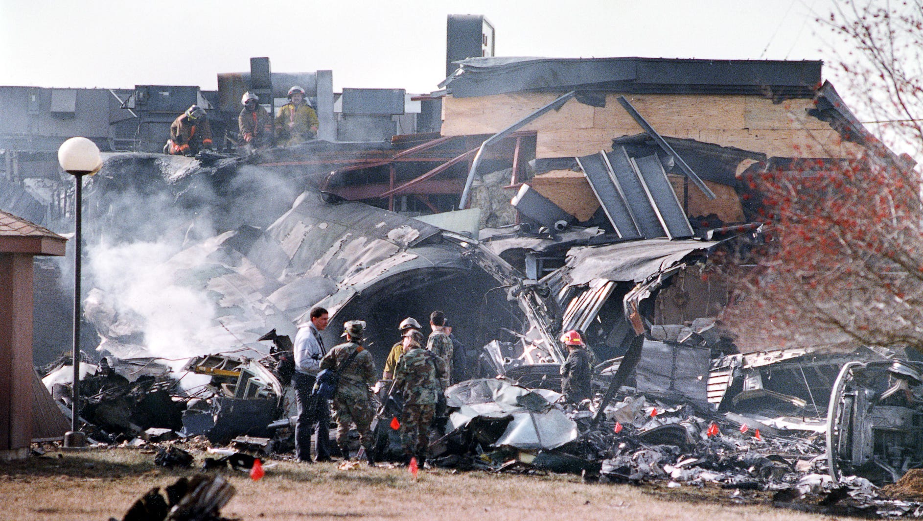 Firefighters examine smoldering wreckage of a C-130B transport plane on the grounds outside a JoJo's Restaurant in Evansville. The plane crashed into the restaurant and a nearby hotel Thursday.