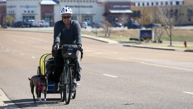 Jasmine Reese and her dog Fiji make their way along Vann Drive on Tuesday. Reese and Fiji left Jackson after a two-night stay to continue their journey to cycle around the world. Reese is currently making her way to Texas.