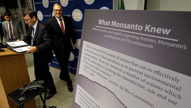 Washington Attorney General Bob Ferguson, left, and Gov. Jay Inslee head into a news conference where Ferguson announced a lawsuit against agrochemical giant Monsanto.