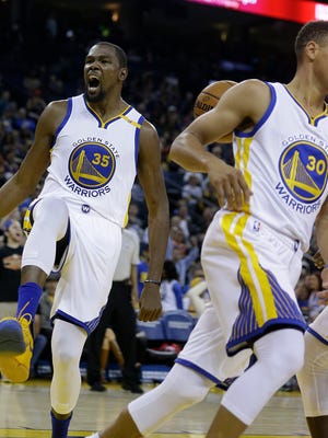 Golden State Warriors' Kevin Durant, left, celebrates after scoring against the Portland Trail Blazers during the second half of a preseason NBA basketball game against the Portland Trail Blazers Friday, Oct. 21, 2016, in Oakland, Calif. At right is Warriors' Stephen Curry (30).