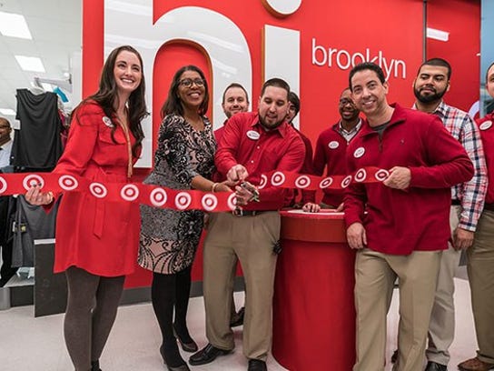 Target employees dressed in red cutting the ribbon for a new Target store grand opening.