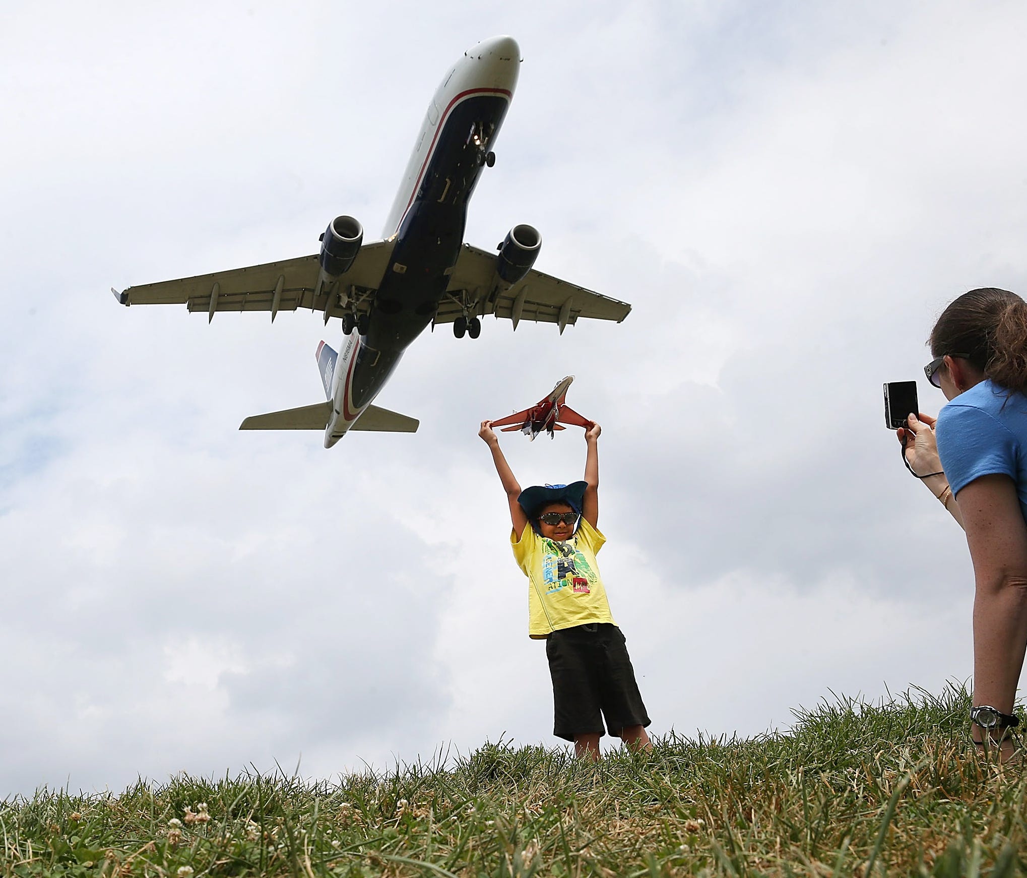 A young boy poses for a picture at Gravelly Point as an airplane flies into Reagan National Airport in Arlington, Virginia.