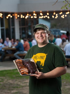 Pitmaster Hunter Ray of Pig & Pint in Fondren shows off a heaping platter of the restaurant's signature barbecue ribs.