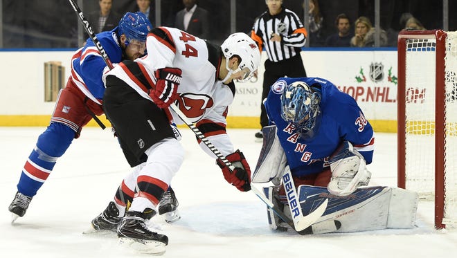 New York Rangers goalie Henrik Lundqvist (30) stopping a shot on goal by New Jersey Devils left wing Miles Wood (44) as Rangers defenseman Kevin Klein (8) defended during Sunday's game.