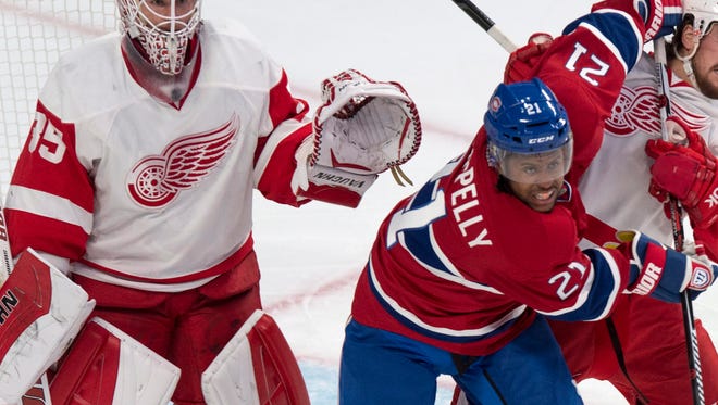 Montreal Canadiens' Devante Smith-Pelly fends off Detroit Red Wings defenseman Brendan Smith in front of goalie Jimmy Howard during the first period of an NHL hockey game, Thursday, April 9, 2015 in Montreal.