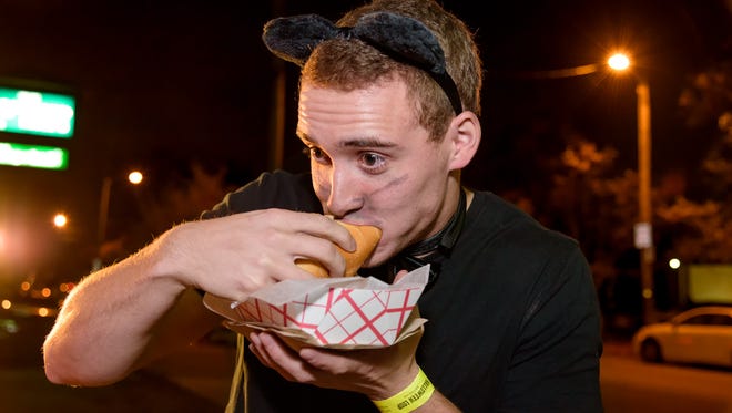 Alex Vanek of Wilmington eats a sandwich from the WiLDWiCH food truck in Trolley Square during the Halloween Loop in Wilmington Saturday night.