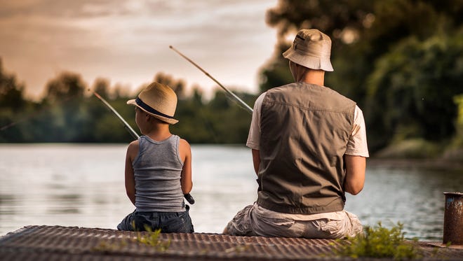 Rear view of a father and son fishing from the pier.