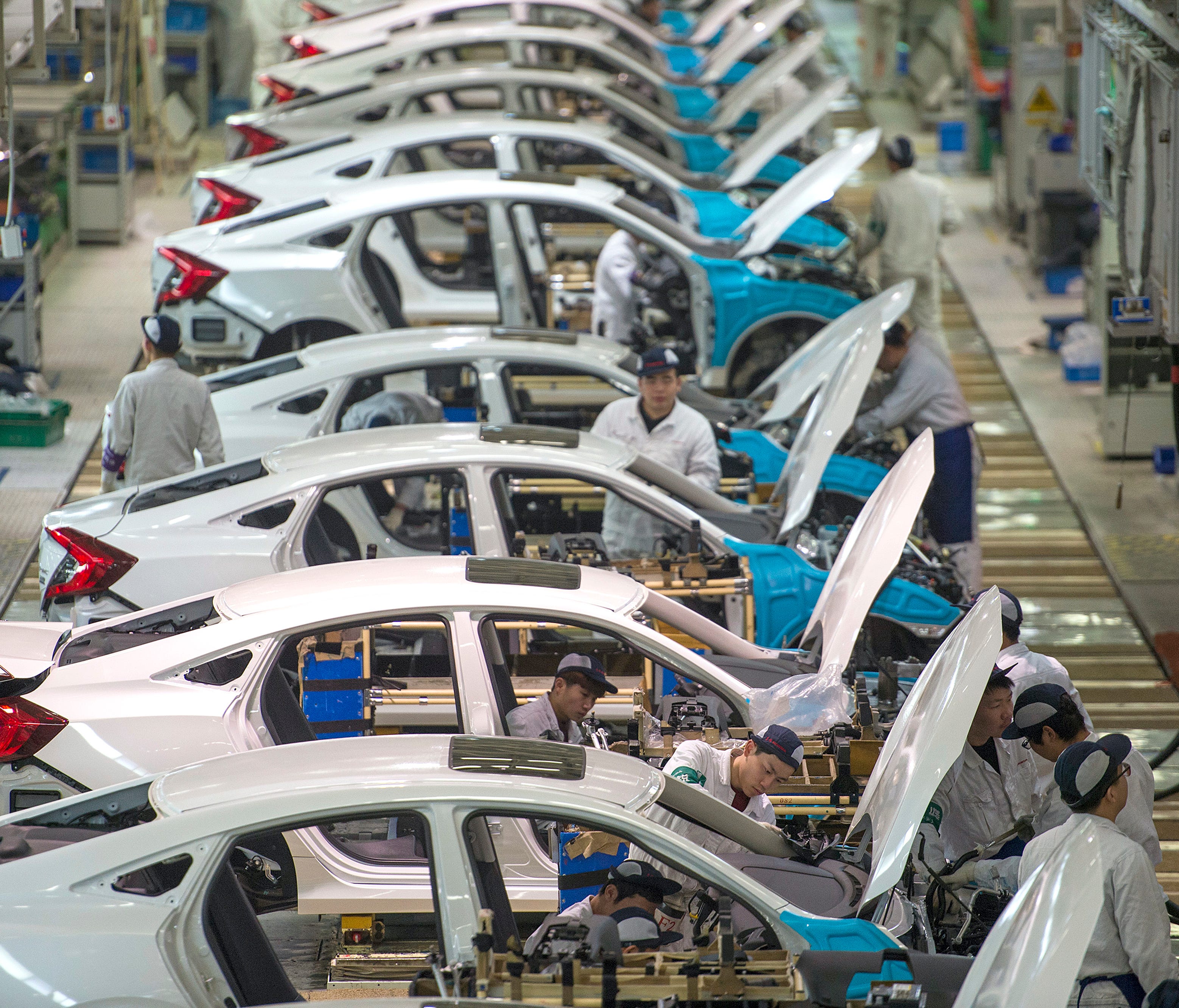 Workers assemble Honda Civics on an assembly line at a Dongfeng Honda automotive plant in Wuhan in central China's Hubei province. China's economy expanded at a 6.9 percent pace in 2017, faster than expected and the first annual increase in seven yea