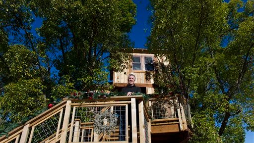 In this Dec. 30 photo, Mike Splinter stands on stairs going up to the treehouse at his home in the Sacramento suburb of Granite Bay, Calif. Splinter's treehouse was recently featured in the show Treehouse Masters, where an expert builder constructs a treehouse at someone's home, but Northern California authorities are telling Splinter and his wife Pat to prune back their deluxe treehouse. The 500-square-foot treehouse features a full kitchen, a bathroom and all the plumbing. But Placer County officials say that the family already has a full guest cottage on their property, so the treehouse's full kitchen and mattress must go.