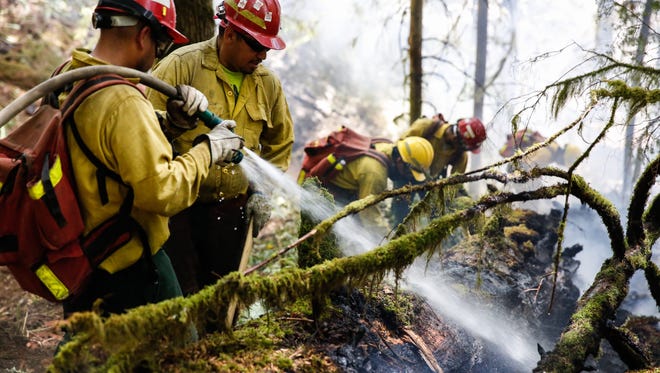 Mario Garcia (left) and José Perez work with a team to extinguish a portion of the Silver Creek Fire in Oregon’s Silver Falls State Park on Saturday, July 14, 2018.