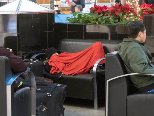 A woman rests as she and others wait in the terminal