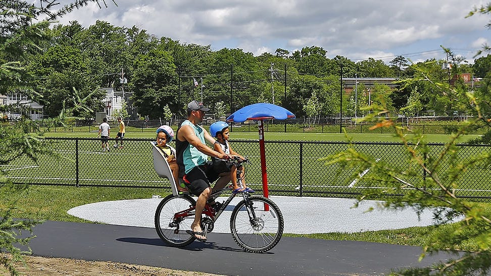 A dad and kids ride through Kincaide Park off water Street in Quincy.