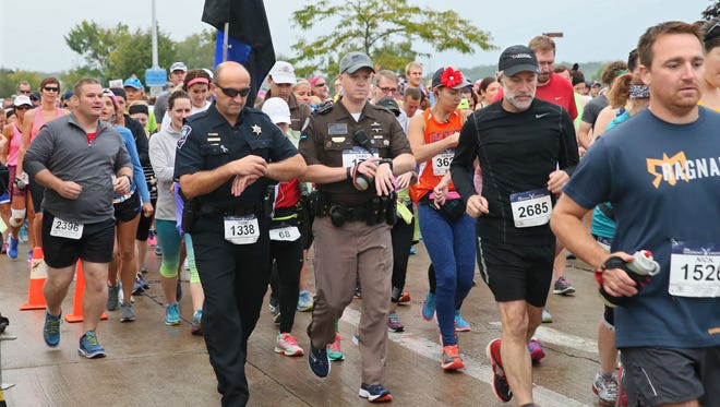 Todd Thomas (left), Appleton chief of police, and Chad Beres (center right) of the Washington County Sheriff's Department set their watches as they begin the Lakefront Marathon on Sunday in Milwaukee.