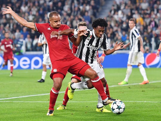 Juventus' Juan Cuadrado, right, and Olympiakos' Vadis Odjidja vie for the ball during the Champions League group D soccer match  between Juventus and Olympiakos, at the Allianz stadium in Turin, Italy, Wednesday, Sept. 27, 2017. (Alessandro Di Marco/ANSA via AP)