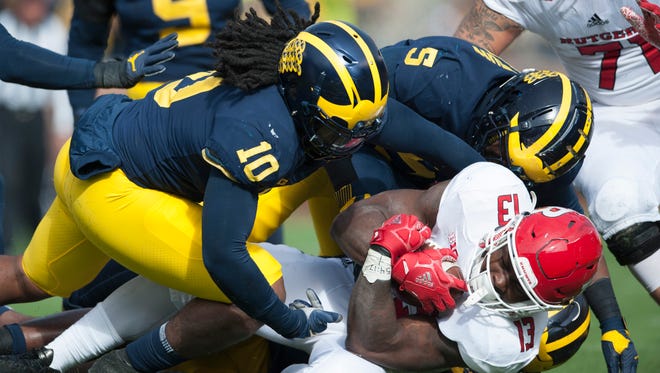 Michigan linebacker Devin Bush (10) and defensive lineman Aubrey Soloman (5) tackle Rutgers running back Gus Edwards for a loss in the first quarter.