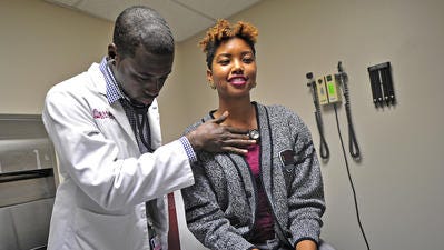 Meharry Medical School student volunteer Abayomi Fabumi, left, checks on patient Jasmine Figgins at a community clinic in 2013.