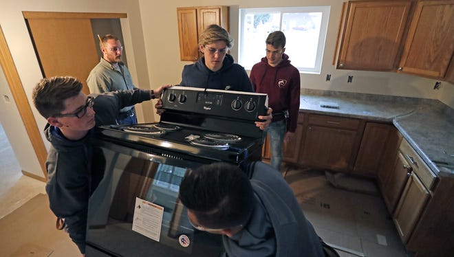 Appleton Area School District school build instructor Marcus McGuire, upper left, oversees the installation of a new stove by students Joe Cust, left, Harrison Tews, Peyton Berlick and Alfonso Paz, right, at a new Habitat for Humanity home in Appleton. Dan Powers/USA TODAY NETWORK-Wisconsin