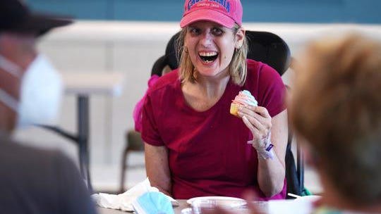 Nicole Carr laughs while eating a birthday cupcake as she sits on the end of a 6-foot-long table during a visitation from her mother Cindy Miramonti of Clinton Township and her brother Chris Carr of Ferndale in the Community Room of the Martha T Berry Medical Care Facility in Mount Clemens on July 13, 2020.