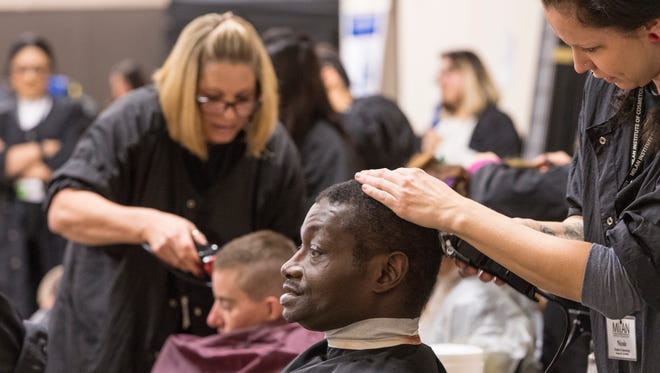 In this 2018 photo,  Milan Institute of Cosmetology student Nicole Shaw gives Maurice Williams a haircut.