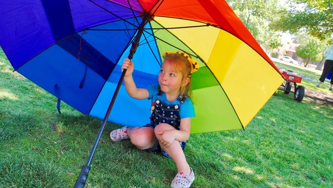 Violet Jaure, 3, shelters under an enormous gay-pride rainbow umbrella, while attending Las Cruces Pride Week activities Saturday June 17, 2017.
