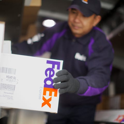 A FedEx delivery person grabs a package off a shel